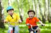 Boldog gyerekek bicikli zöld liget Stock fotográfiák